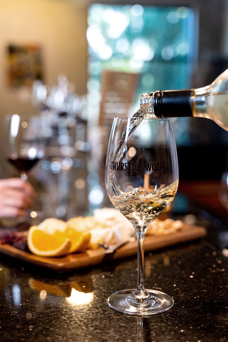 White wine pouring into a glass on table.
