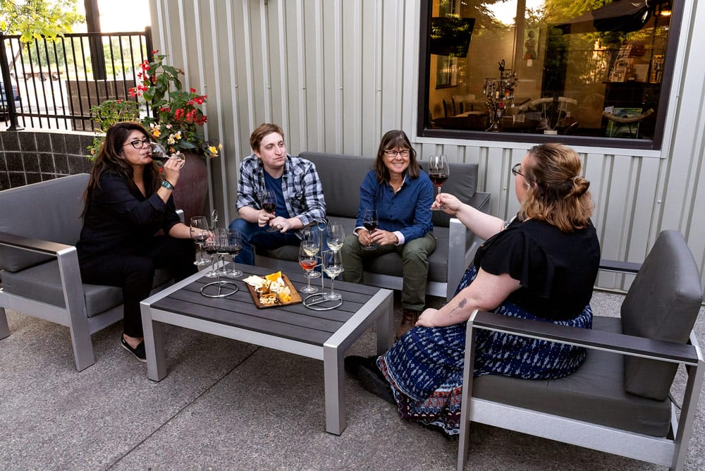 Group enjoying wine and cheese outside on patio.
