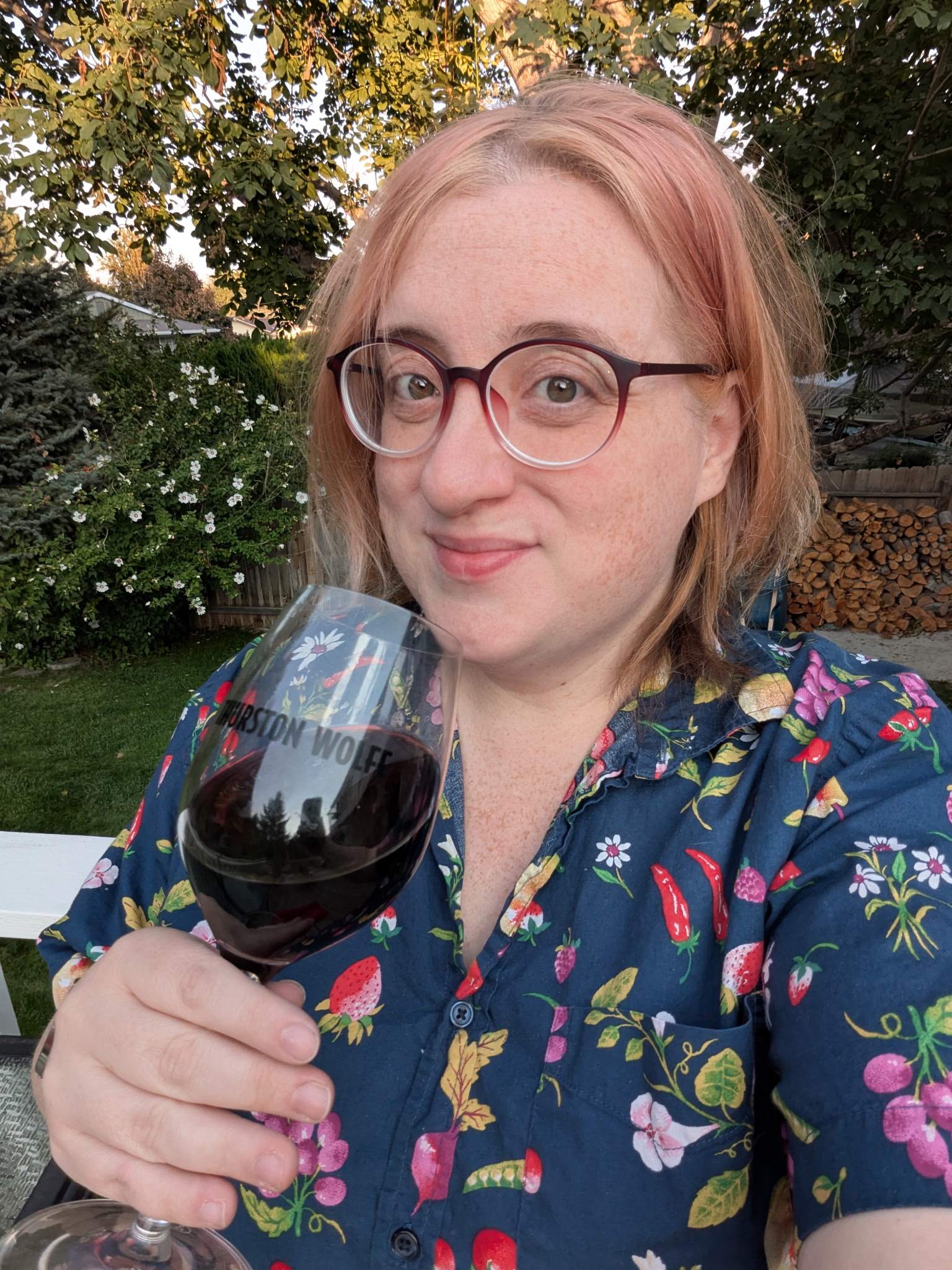 Person holding wine glass in garden.
