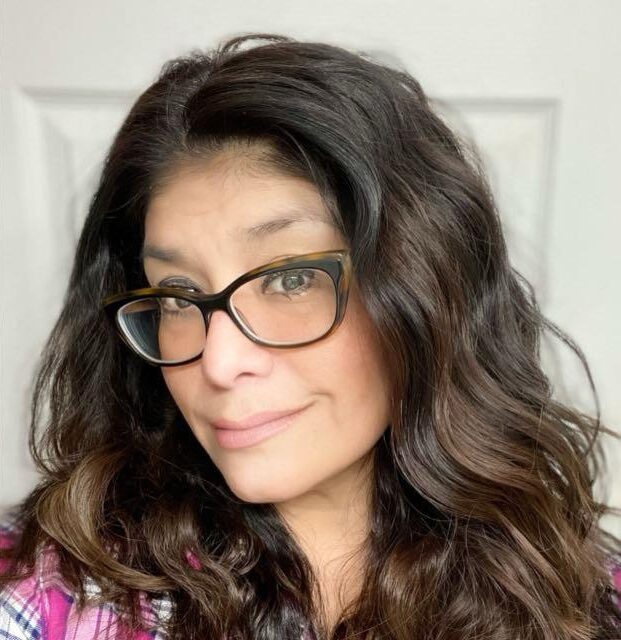 Smiling person with glasses and curly hair.