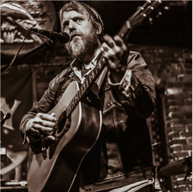 Musician playing guitar on stage.