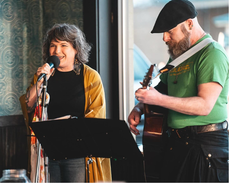 Singer and guitarist performing in a cozy venue.
