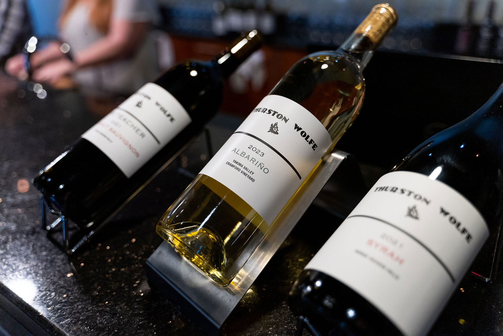 Three bottles of wine on display rack.