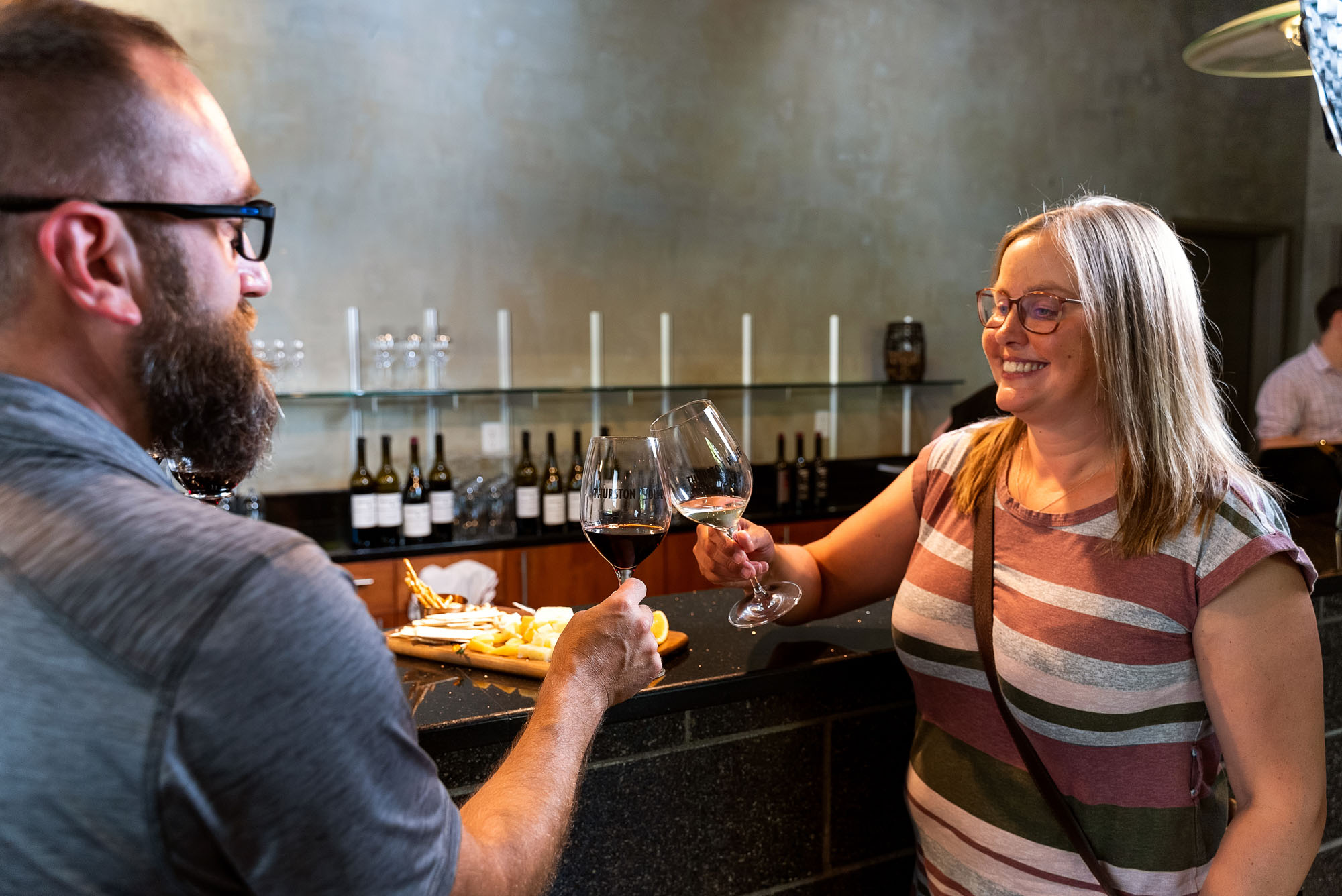 Couple toasting with wine at a bar.