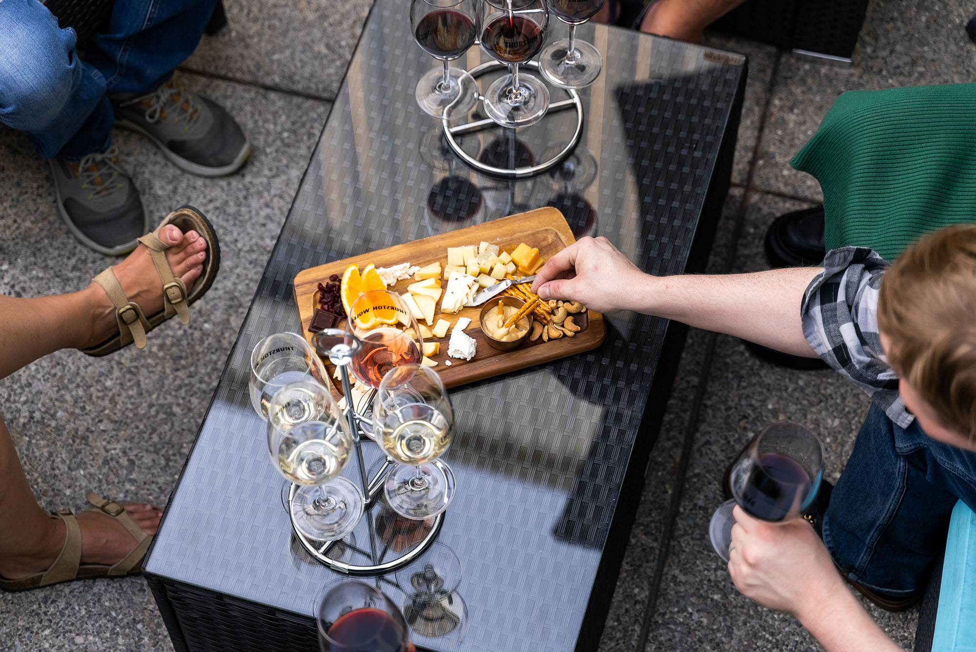 People enjoying wine and cheese on patio table.
