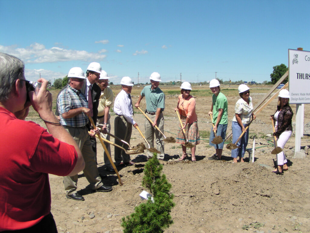 Group at groundbreaking ceremony with shovels and helmets.
