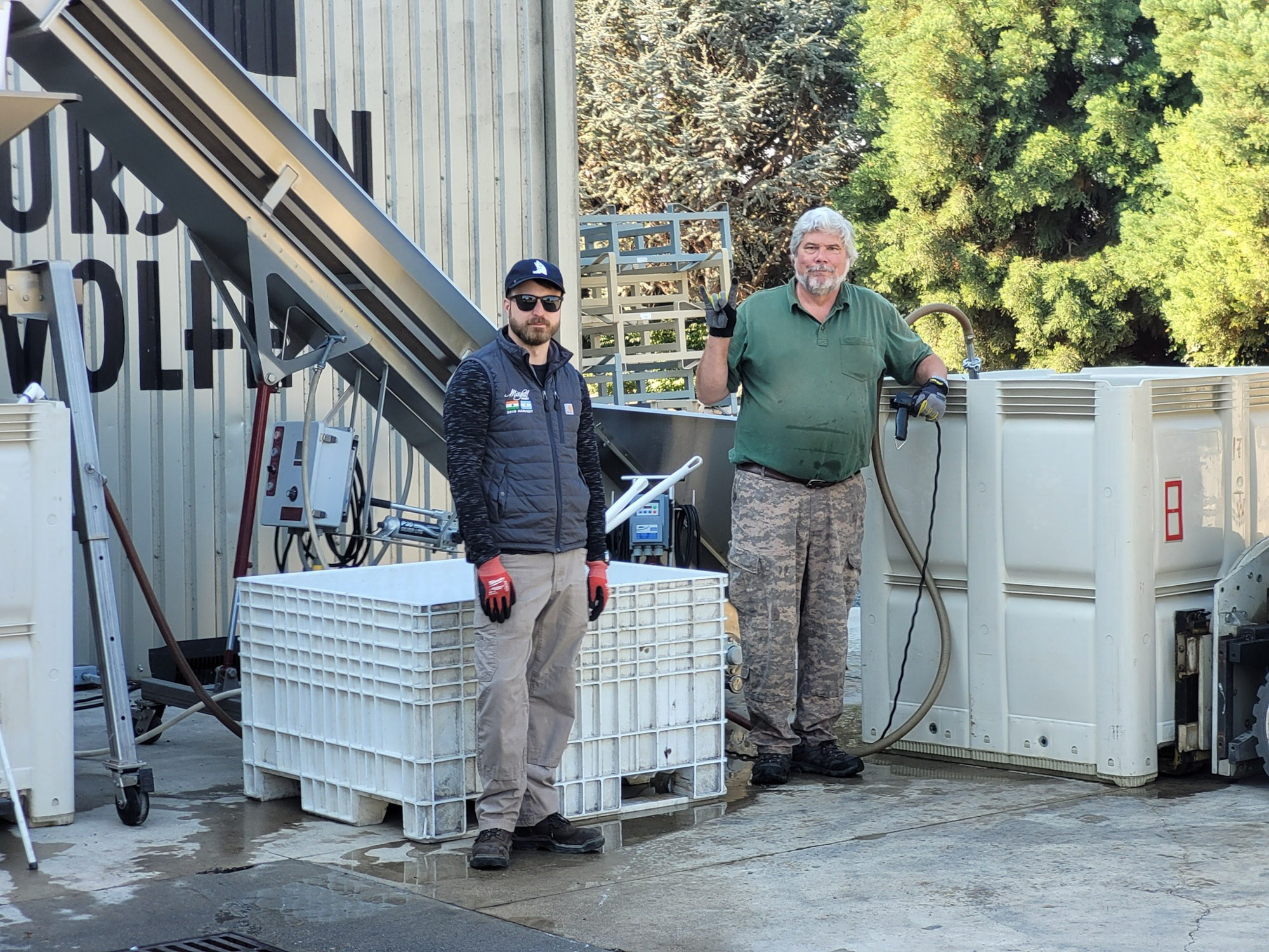 Two men at industrial facility with equipment.